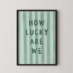 a framed poster with the text "HOW LUCKY ARE WE" written on it.