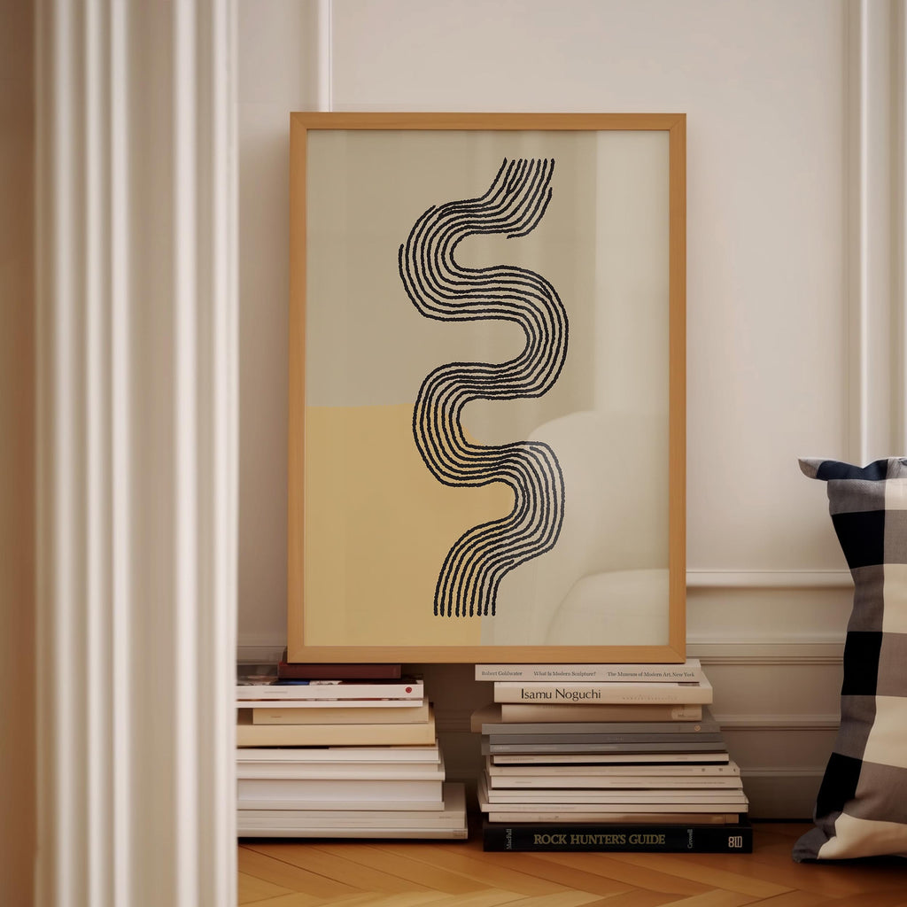 a framed abstract artwork with a black and white design, placed on a shelf next to a stack of books.