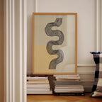 a framed abstract artwork with a black and white design, placed on a shelf next to a stack of books.