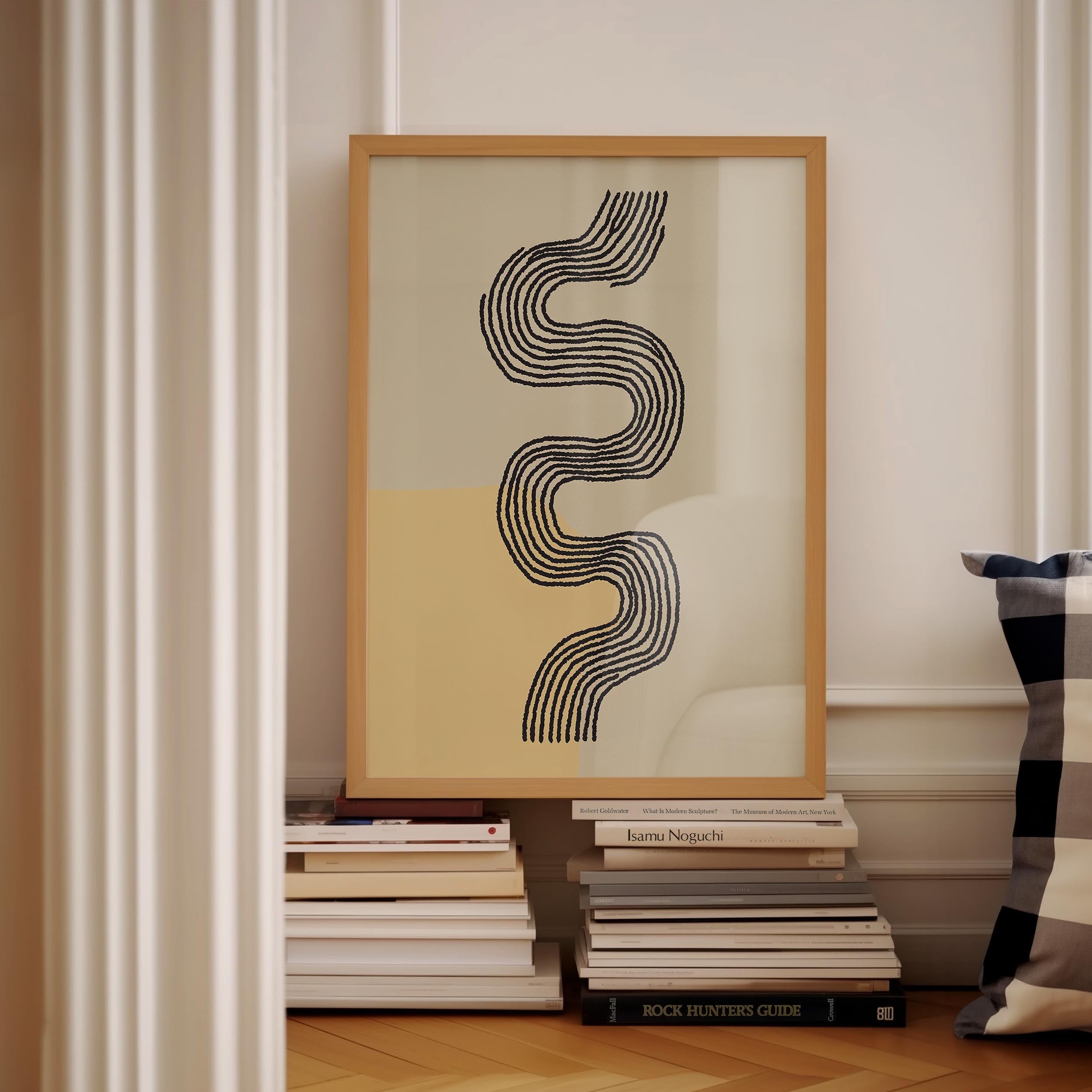 a framed abstract artwork with a black and white design, placed on a shelf next to a stack of books.