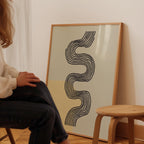 A person is sitting on a chair in front of a large abstract artwork featuring a wavy line design.