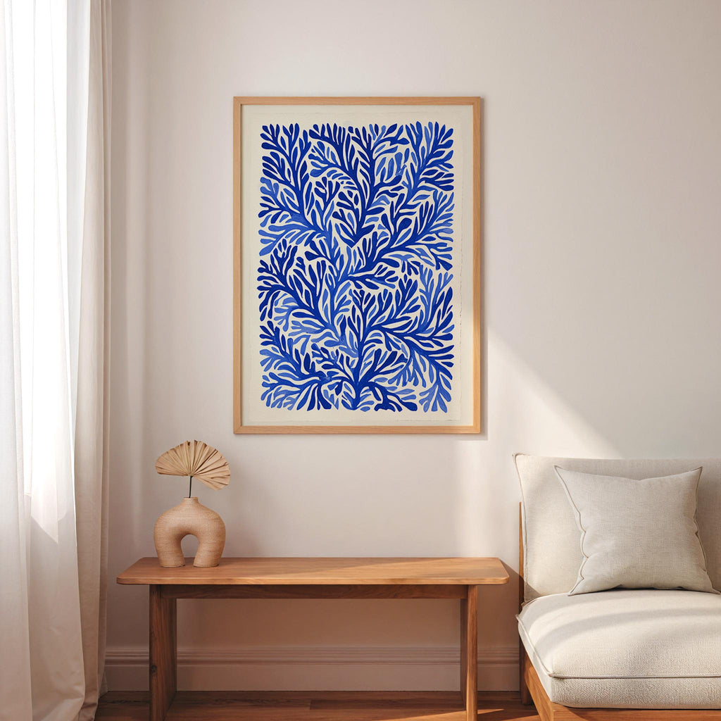 a living room with a large blue and white abstract painting hanging on the wall above a wooden table with a fan-shaped vase on it. The table is positioned next to a white sofa, creating a cozy and inviting atmosphere.