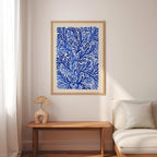 a living room with a large blue and white abstract painting hanging on the wall above a wooden table with a fan-shaped vase on it. The table is positioned next to a white sofa, creating a cozy and inviting atmosphere.