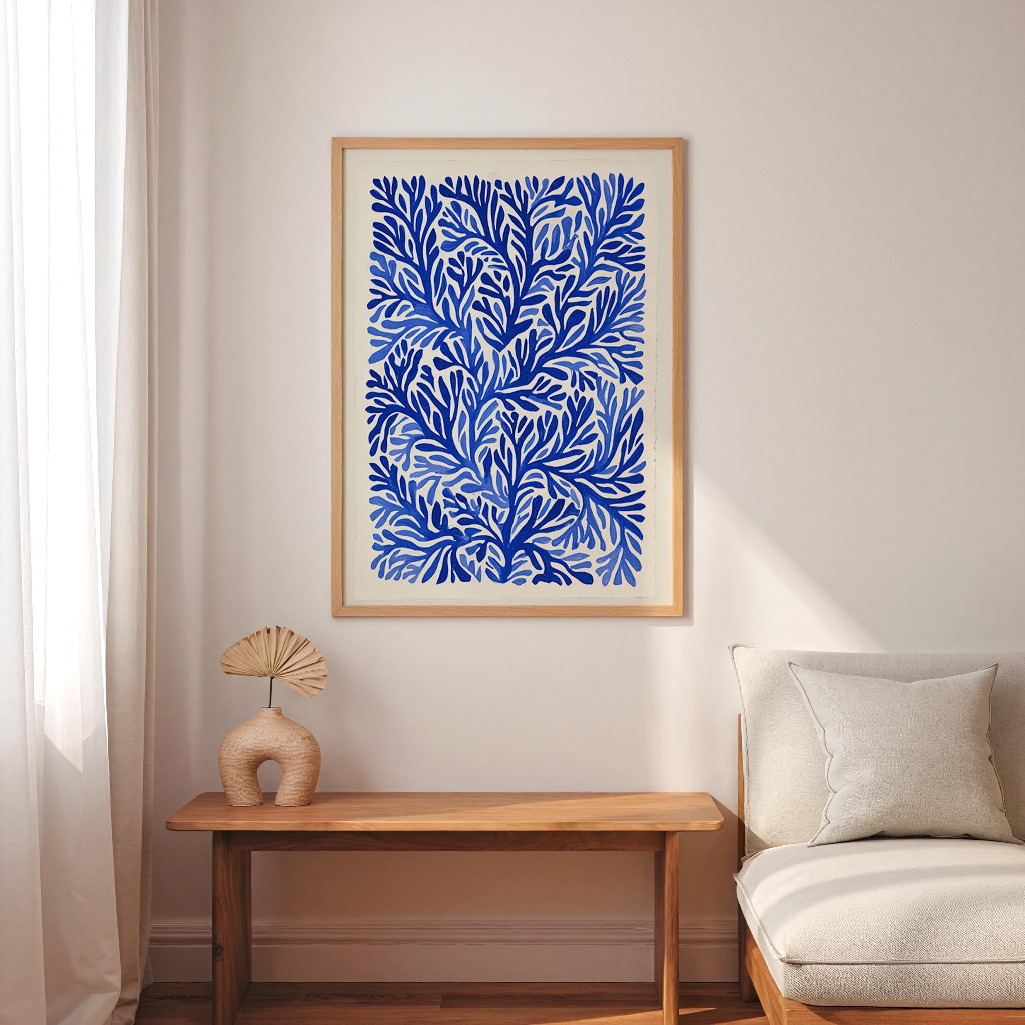 a living room with a large blue and white abstract painting hanging on the wall above a wooden table with a fan-shaped vase on it. The table is positioned next to a white sofa, creating a cozy and inviting atmosphere.