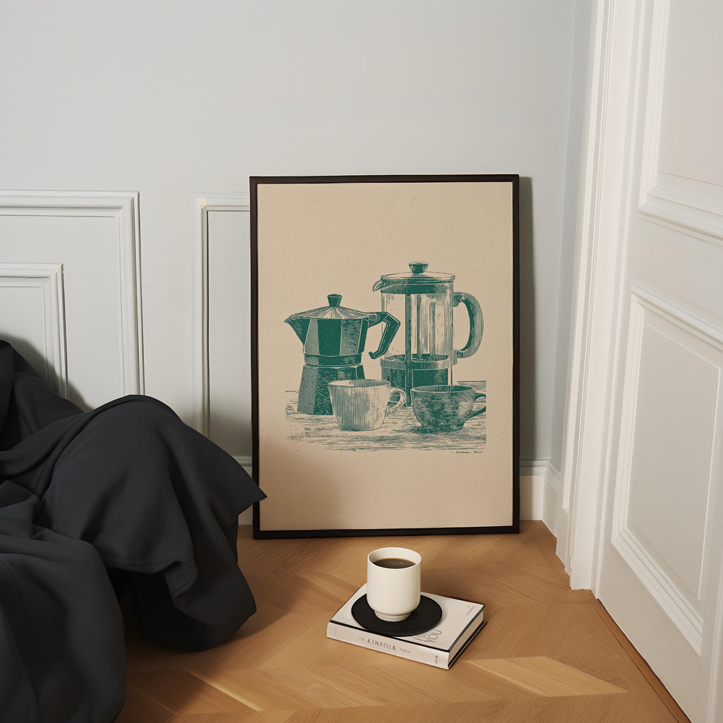 a framed illustration of a coffee maker and two cups on a wooden floor, with a book and a cup of coffee placed nearby.