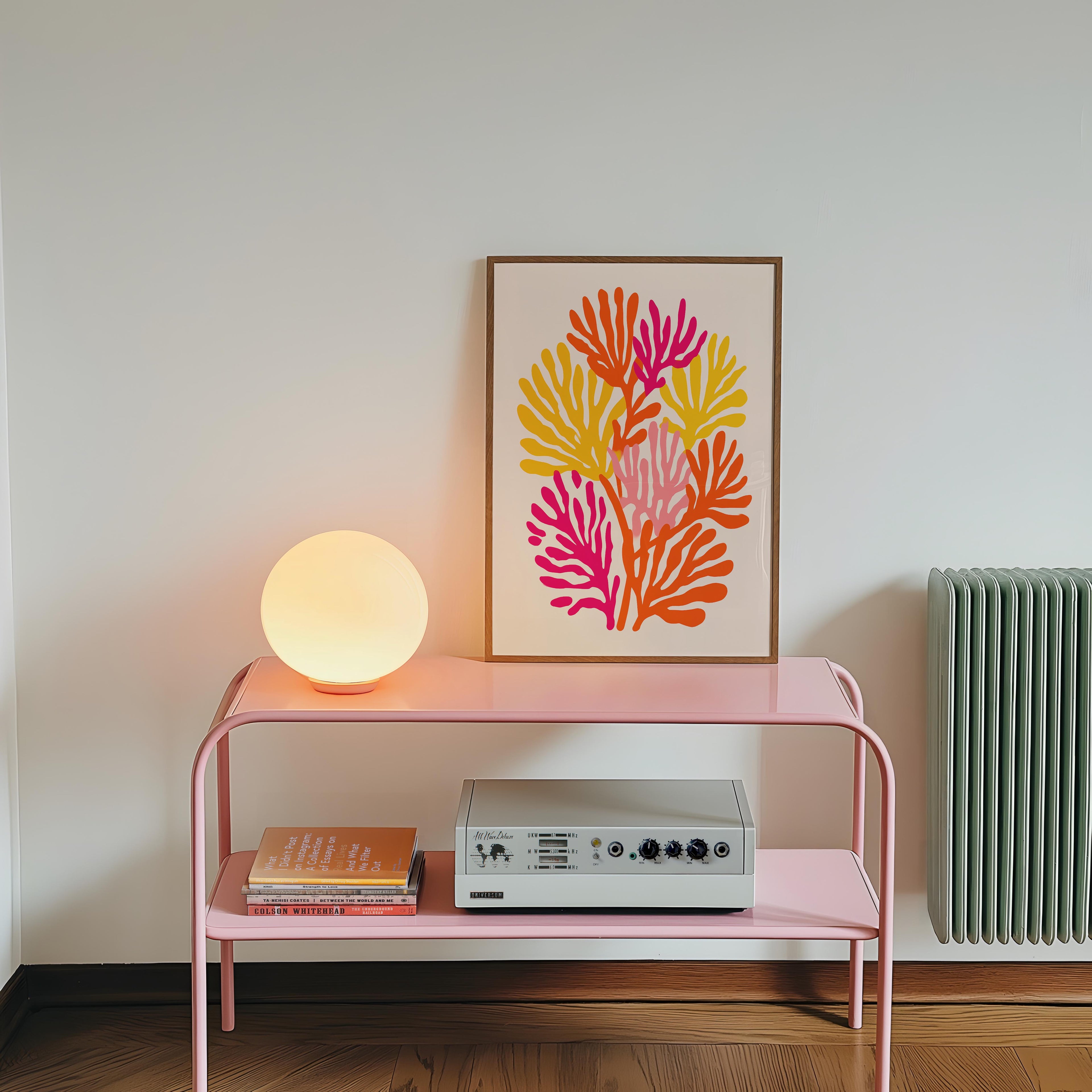 a pink metal table with a framed artwork of colorful flowers on it, a lamp, and a radio on the lower shelf.