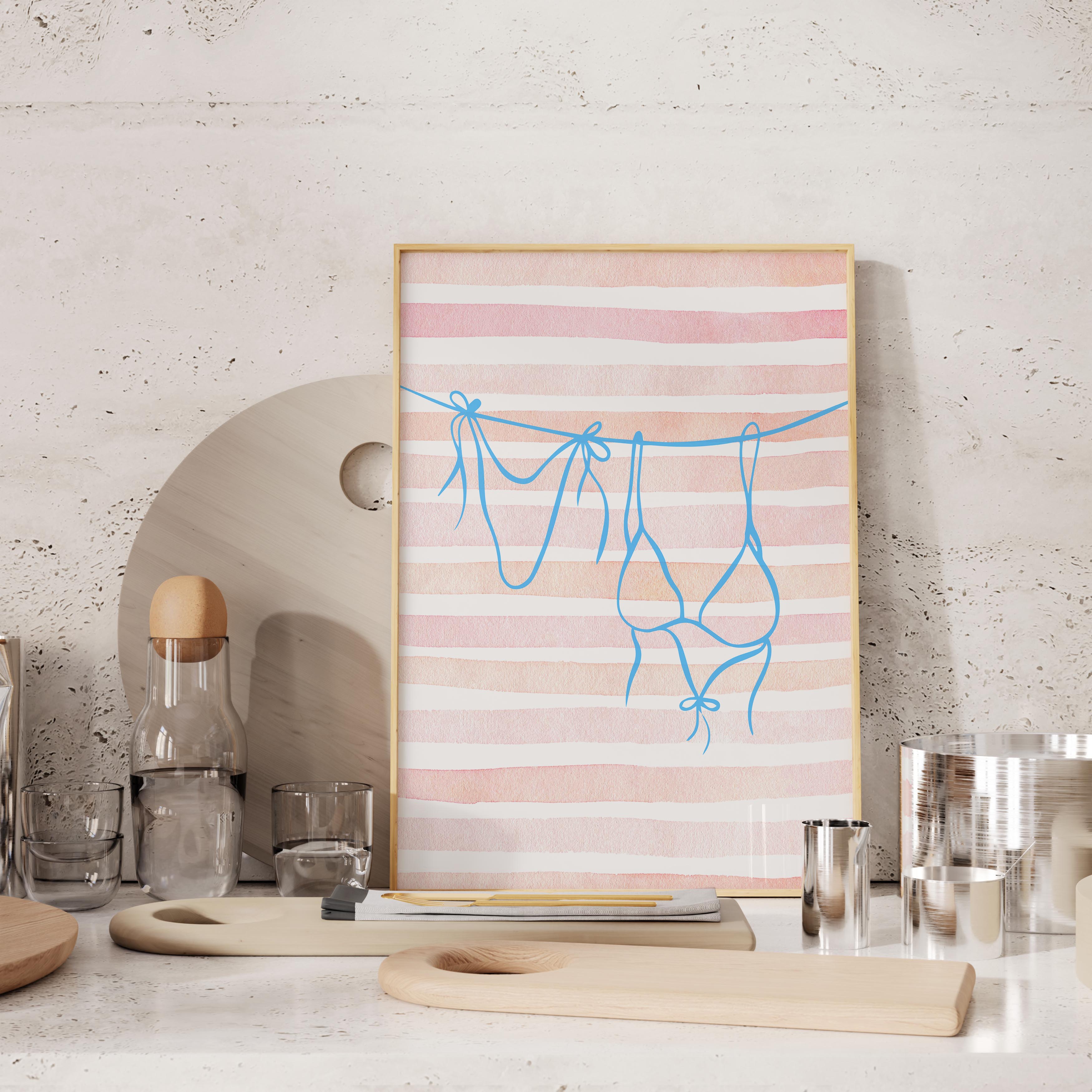 a framed artwork with a pink and white striped background, depicting a pair of blue underwear hanging on a clothesline. The artwork is displayed on a shelf, surrounded by various kitchen items such as a bottle, a glass, and a wooden cutting board.