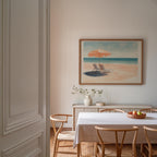 a serene dining room with a white table and chairs, a framed painting of a beach scene, and a vase of flowers on the table.
