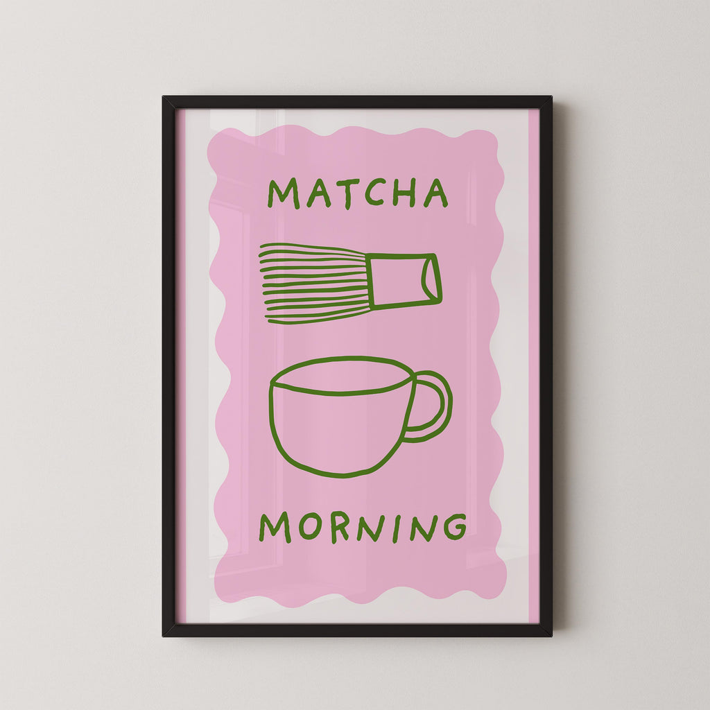 The image is a framed poster with a pink background and a green cup and whisk illustration. The text "MATCHA MORNING" is displayed above the illustration.