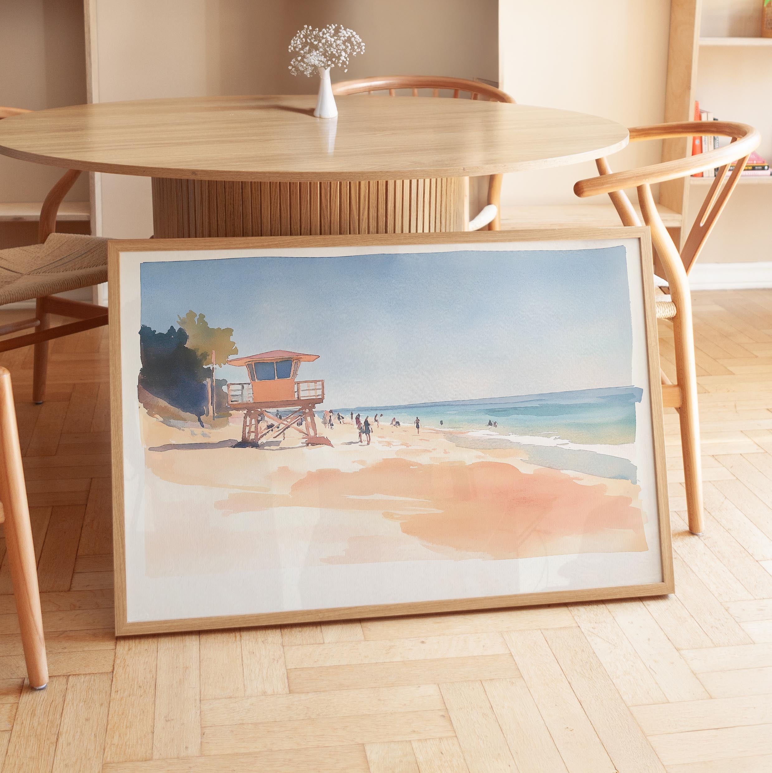 a framed painting of a beach scene with a lifeguard tower and people enjoying the beach.