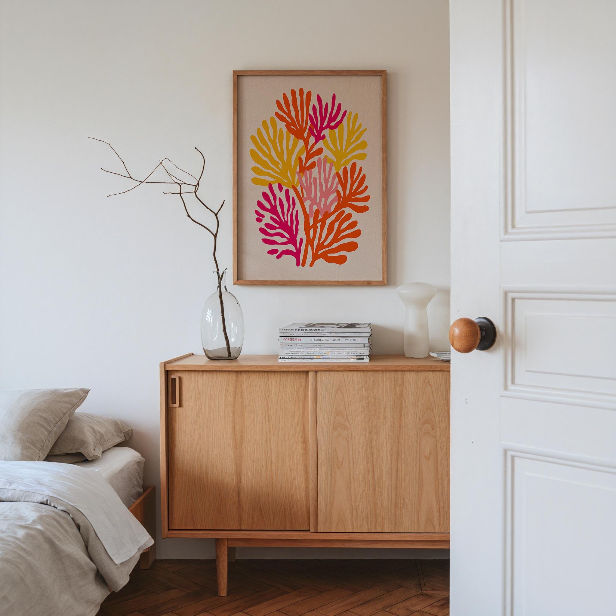 a bedroom with a wooden cabinet, a framed artwork featuring a colorful floral design, and a bed with a white comforter.