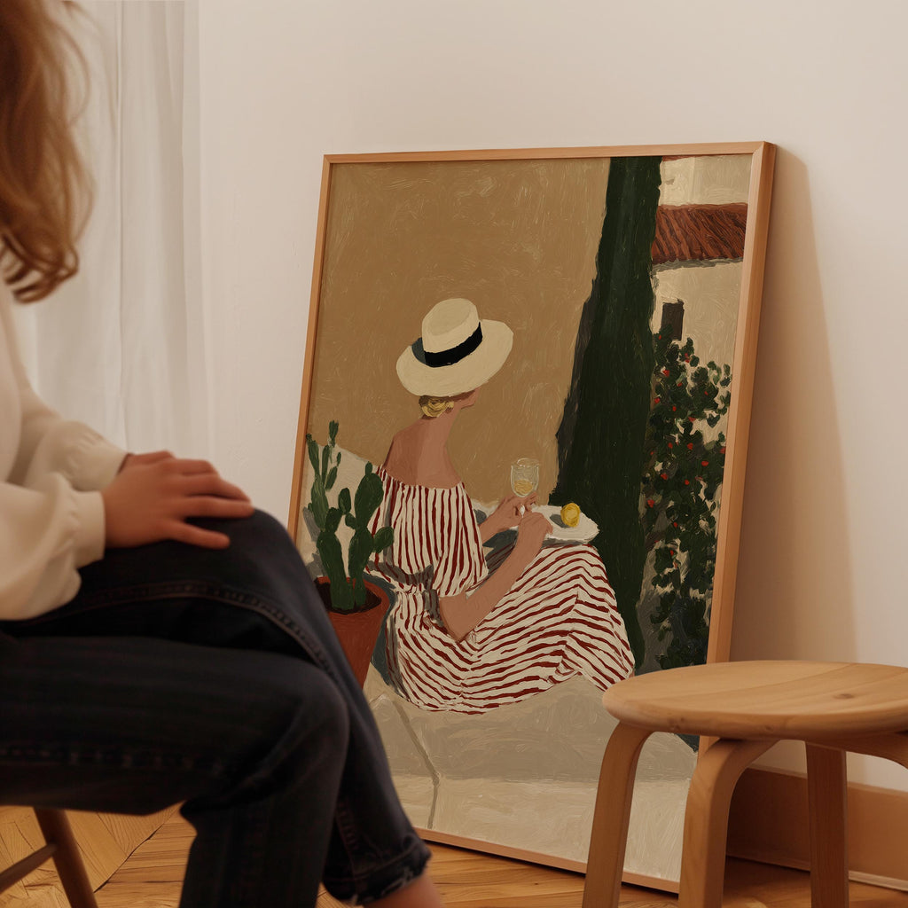 A person is sitting in front of a painting that depicts a woman in a striped dress and hat, holding a glass of wine and a plate of food.