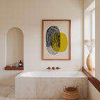 a modern bathroom with a large white bathtub, a wooden shelf, and a framed abstract artwork on the wall.