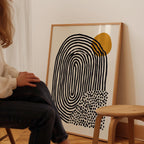 A person is sitting in a chair in front of a large abstract painting on the wall.