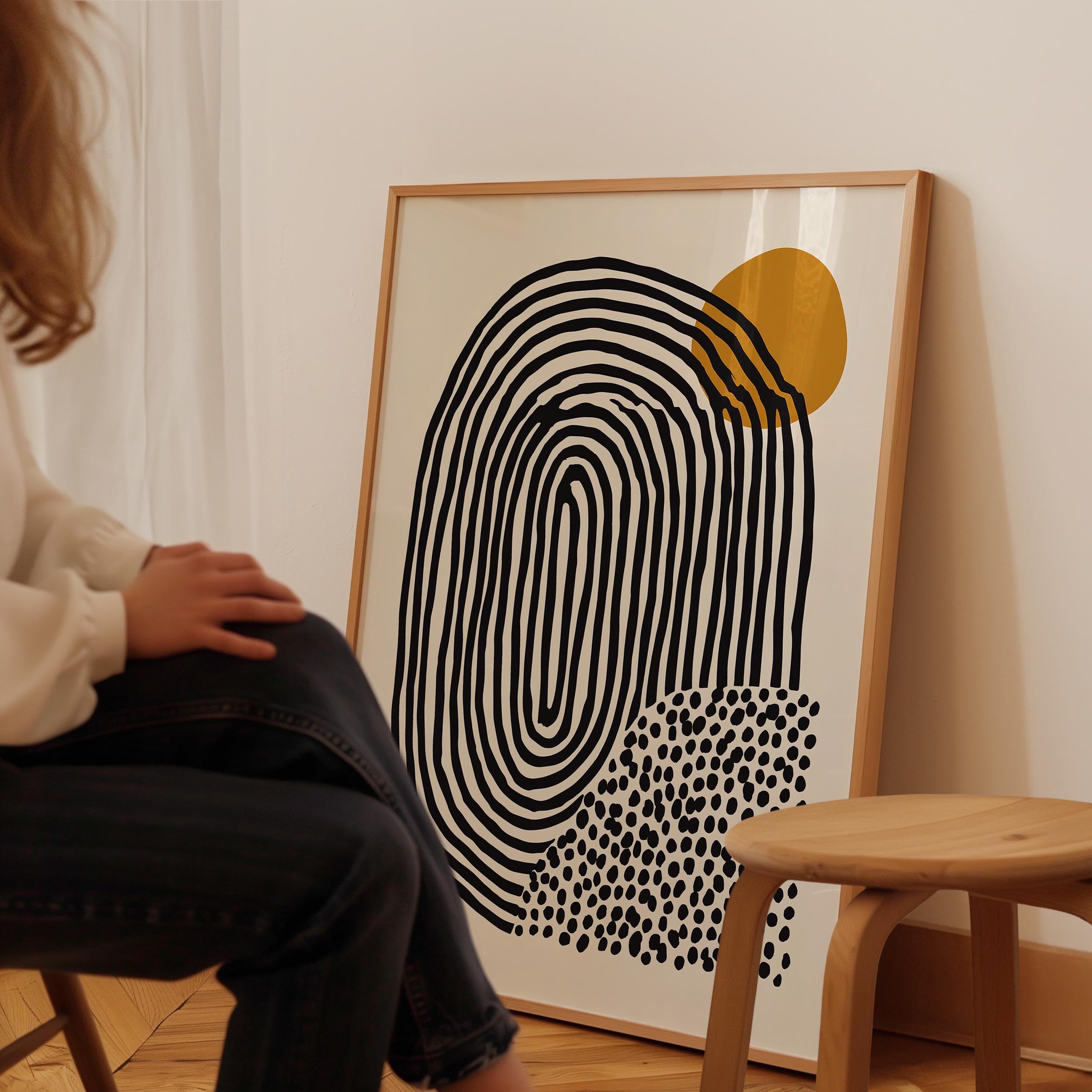 A person is sitting in a chair in front of a large abstract painting on the wall.