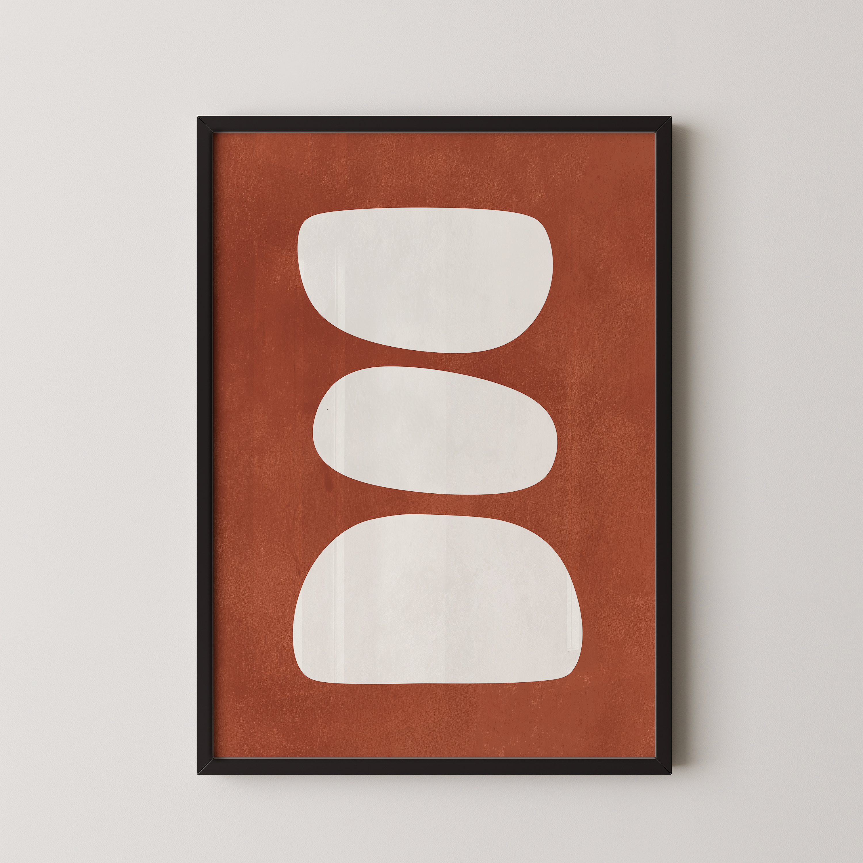 a framed abstract art piece with a brown background and three white shapes arranged in a row.