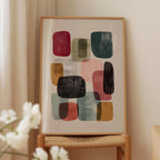 a framed abstract art piece with various colored shapes and forms, displayed on a wooden stand.