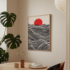 a minimalist dining area with a wooden table, a vase with flowers, and a framed artwork depicting a red sun on a black and white wave-like background.