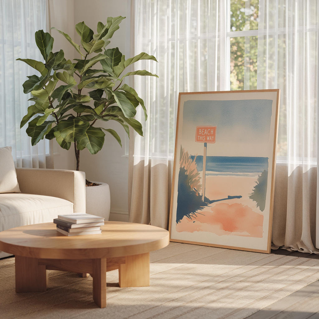 a cozy living room with a large potted plant, a wooden coffee table, and a framed artwork of a beach scene.