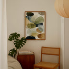 a cozy corner of a room with a wooden chair, a wooden side table, and a framed abstract painting hanging on the wall.