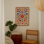 a cozy corner of a room with a wooden chair, a wooden side table, and a framed colorful floral print hanging on the wall.