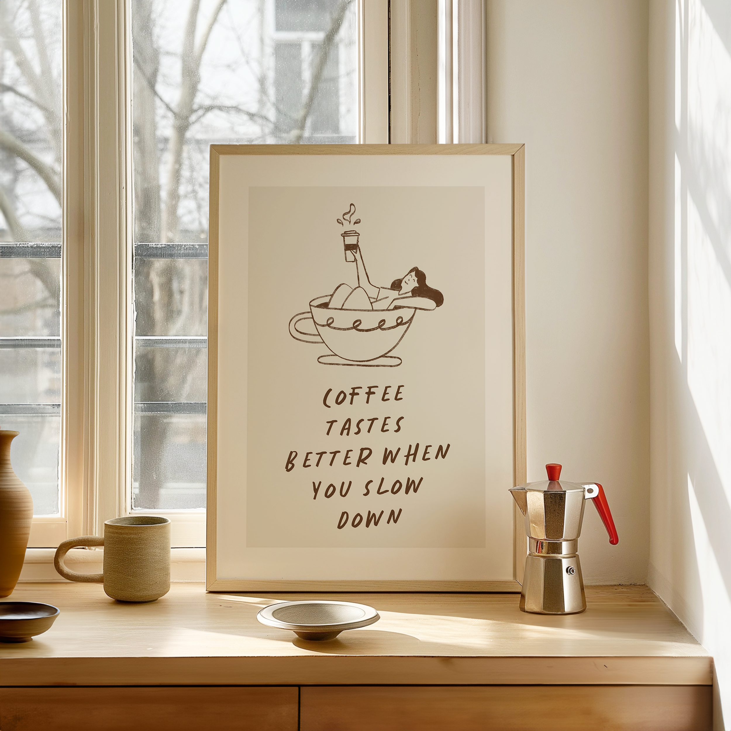 a framed poster with a cartoon illustration of a woman in a cup of coffee, accompanied by the text "Coffee tastes better when you slow down". The poster is displayed on a wooden shelf, with a coffee maker and other decorative items visible in the background.
