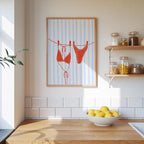 a kitchen counter with a bowl of lemons, a framed picture of a red bikini, and a shelf with jars and containers.