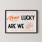 a framed poster with the text "How LUCKY ARE WE" and two dice graphics.