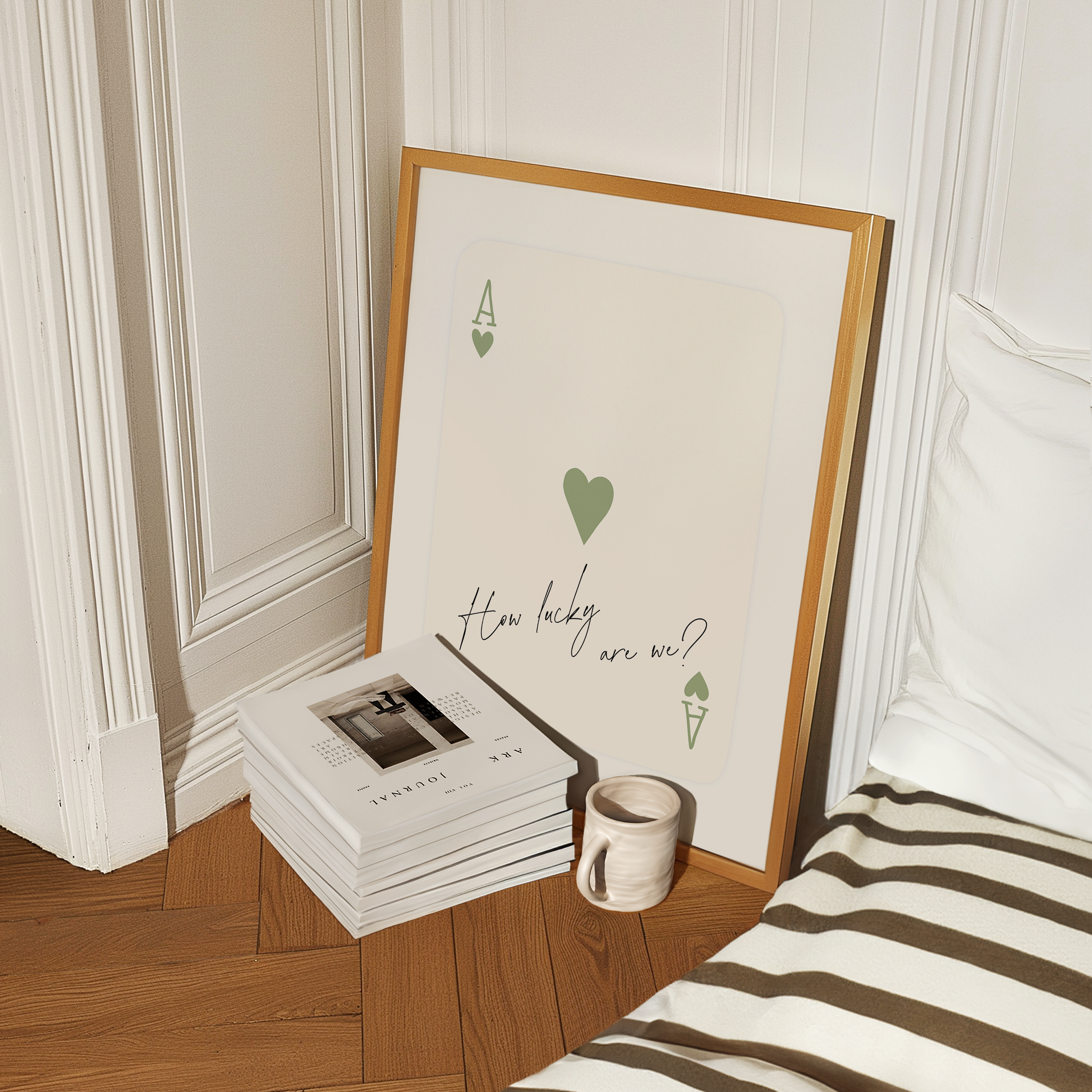 a framed poster with a heart and the text "How lucky are we?" placed on a wooden floor next to a stack of books and a coffee mug.