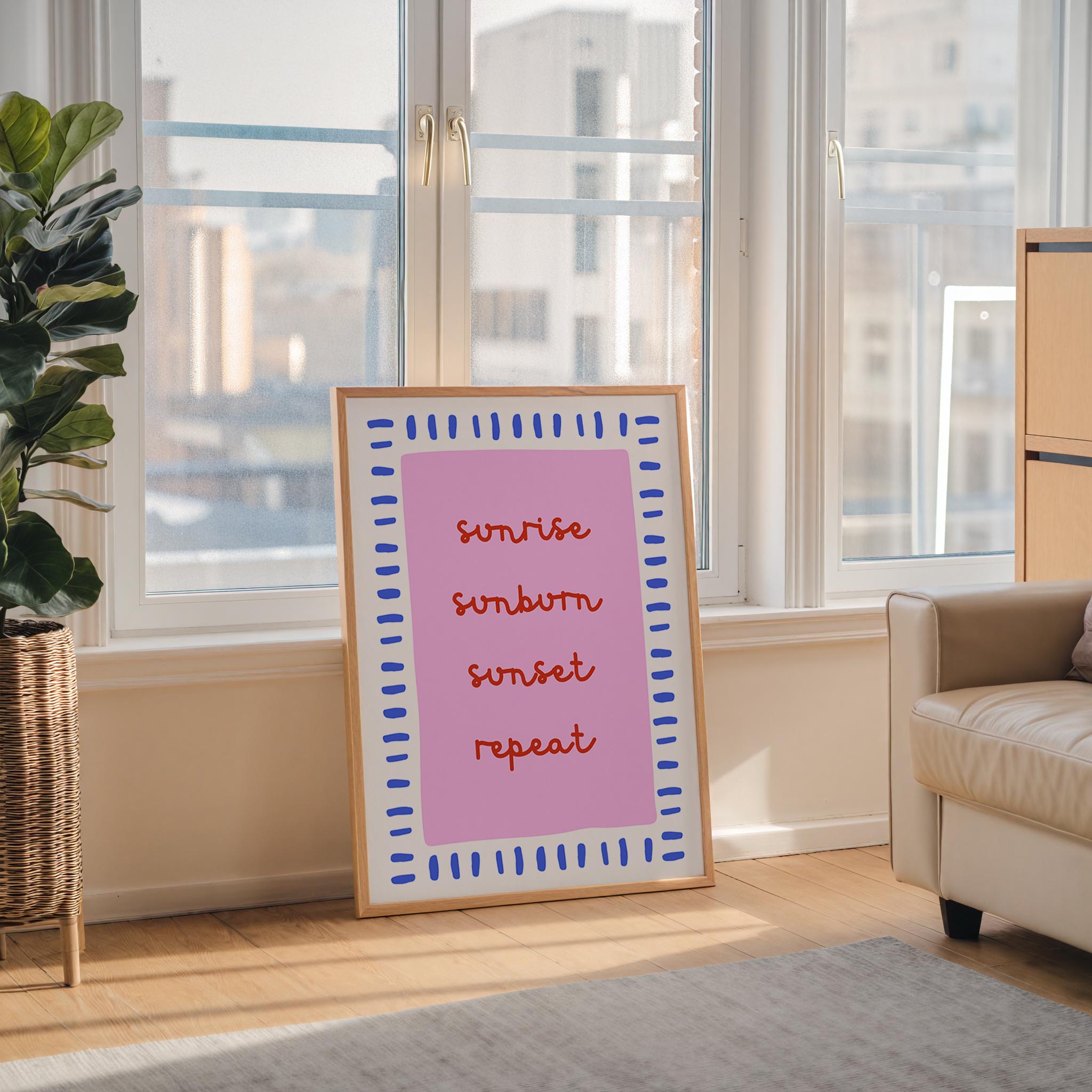 a poster with the text "sunrise, sunset, repeat" in a pink and blue frame, placed in a living room near a window.