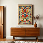 a wooden cabinet with a vase of flowers on top, and a framed colorful floral print hanging on the wall above it.