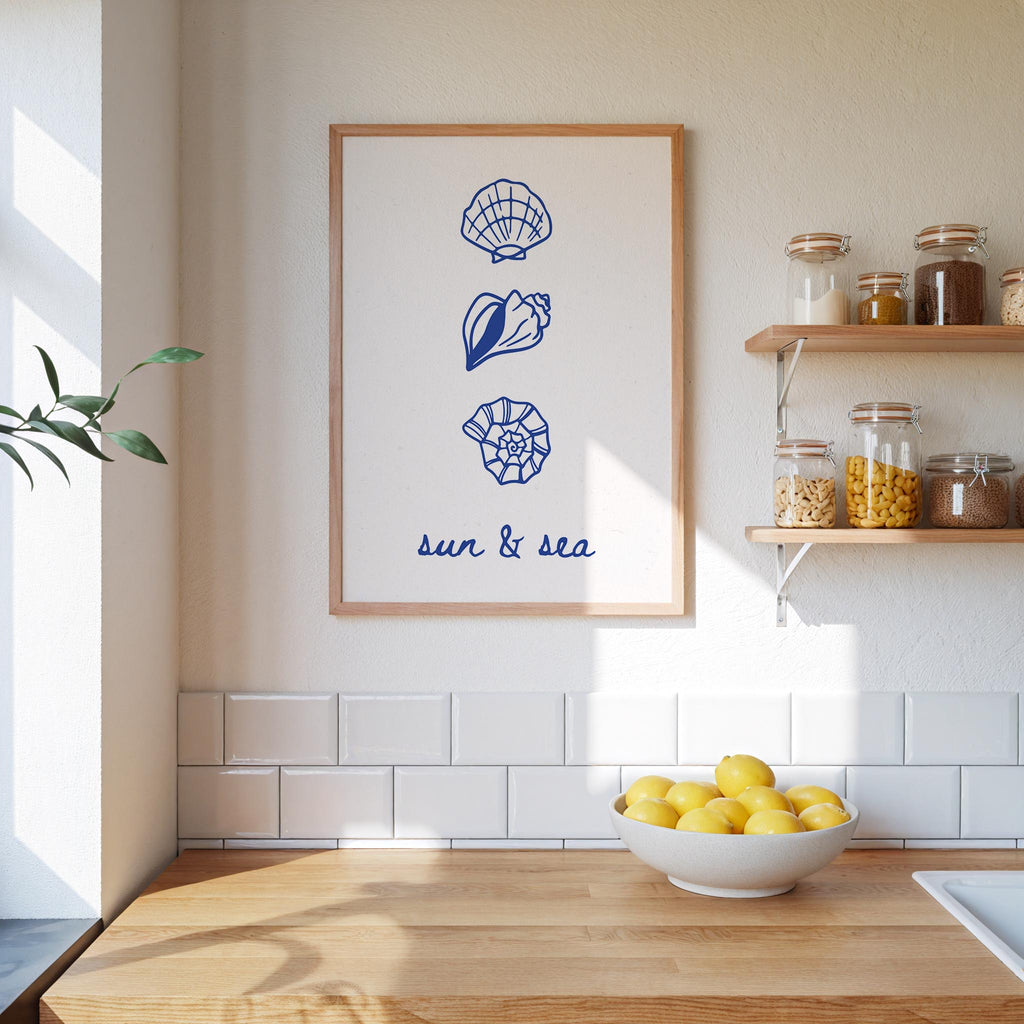 a kitchen counter with a bowl of lemons, a framed poster with seashells and a plant, and a shelf with jars and other kitchen items.