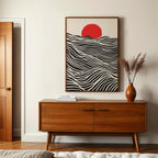 a wooden cabinet with a framed abstract artwork hanging above it, and a vase of dried flowers on a table below the cabinet.