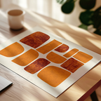 a white piece of paper with a geometric pattern of orange and brown shapes, placed on a wooden surface.