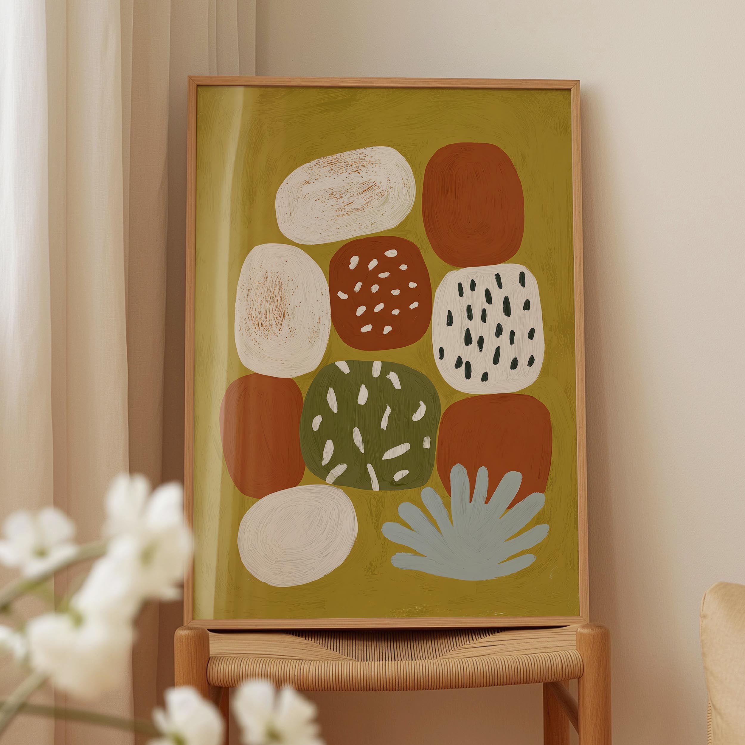 a framed abstract art piece with various shapes and colors, including white, orange, green, and brown, displayed on a wooden stand.