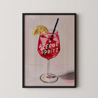 A framed illustration of a red drink with the text "Aperol Spritz" on it, accompanied by a lemon slice.