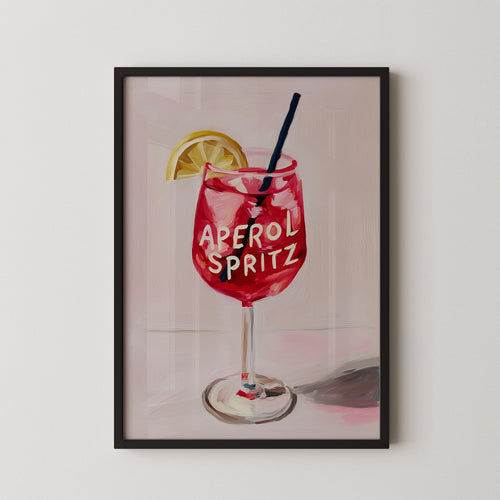 A framed illustration of a red drink with the text "Aperol Spritz" on it, accompanied by a lemon slice.