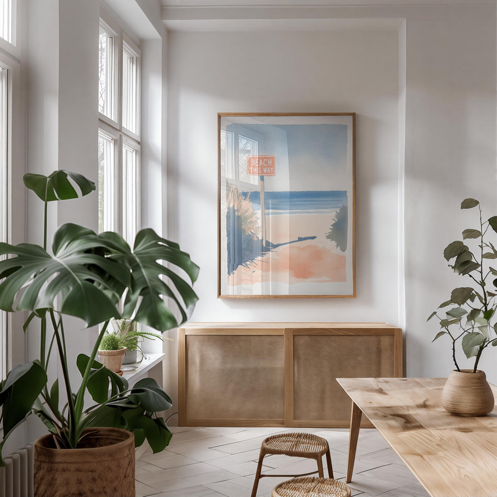 a bright and airy living room with a large window, a wooden cabinet, and a framed picture of a beach scene hanging on the wall.