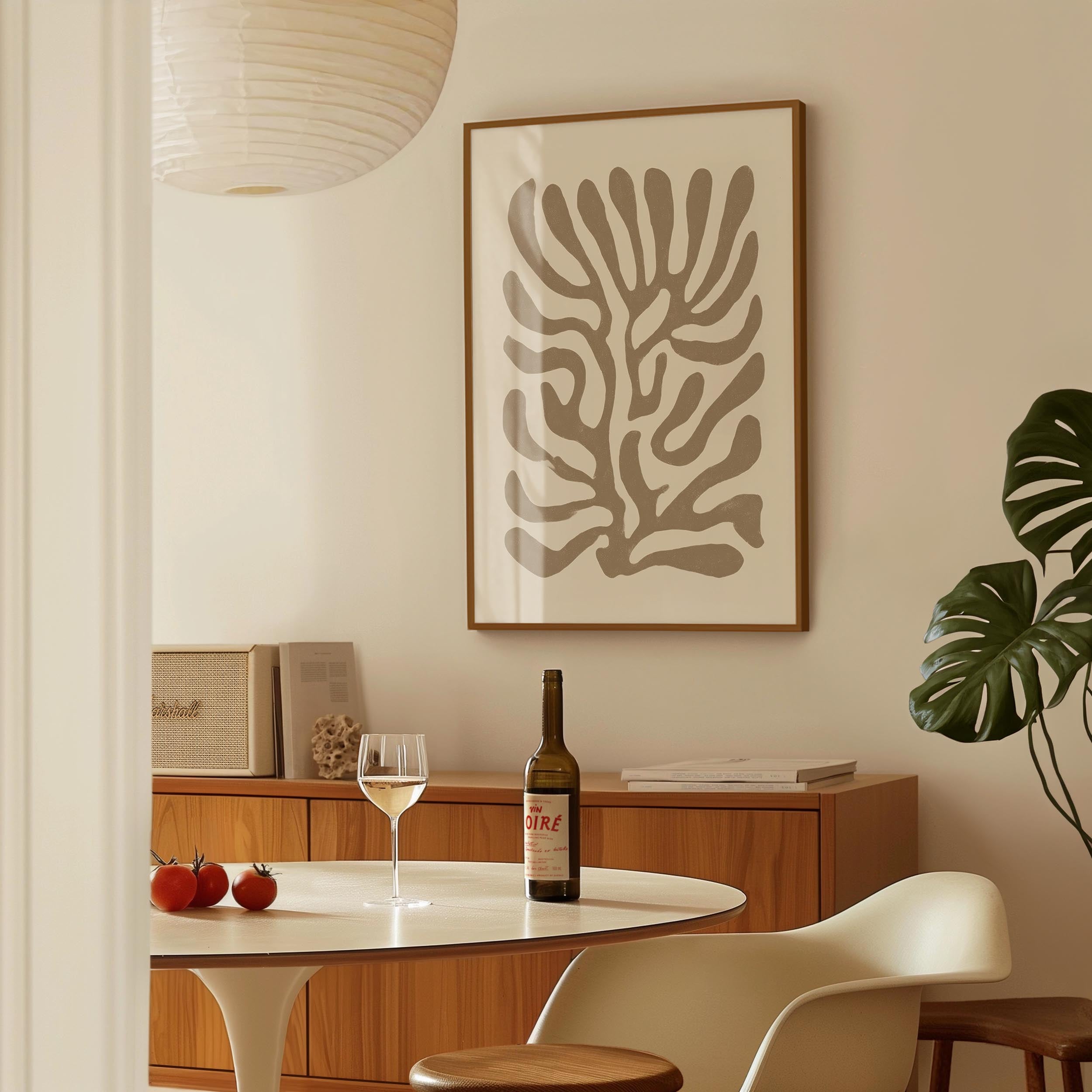 a dining area with a table, a bottle of wine, and a framed abstract art piece on the wall.