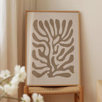 a framed abstract art piece with a stylized tree-like design in shades of gray and brown.