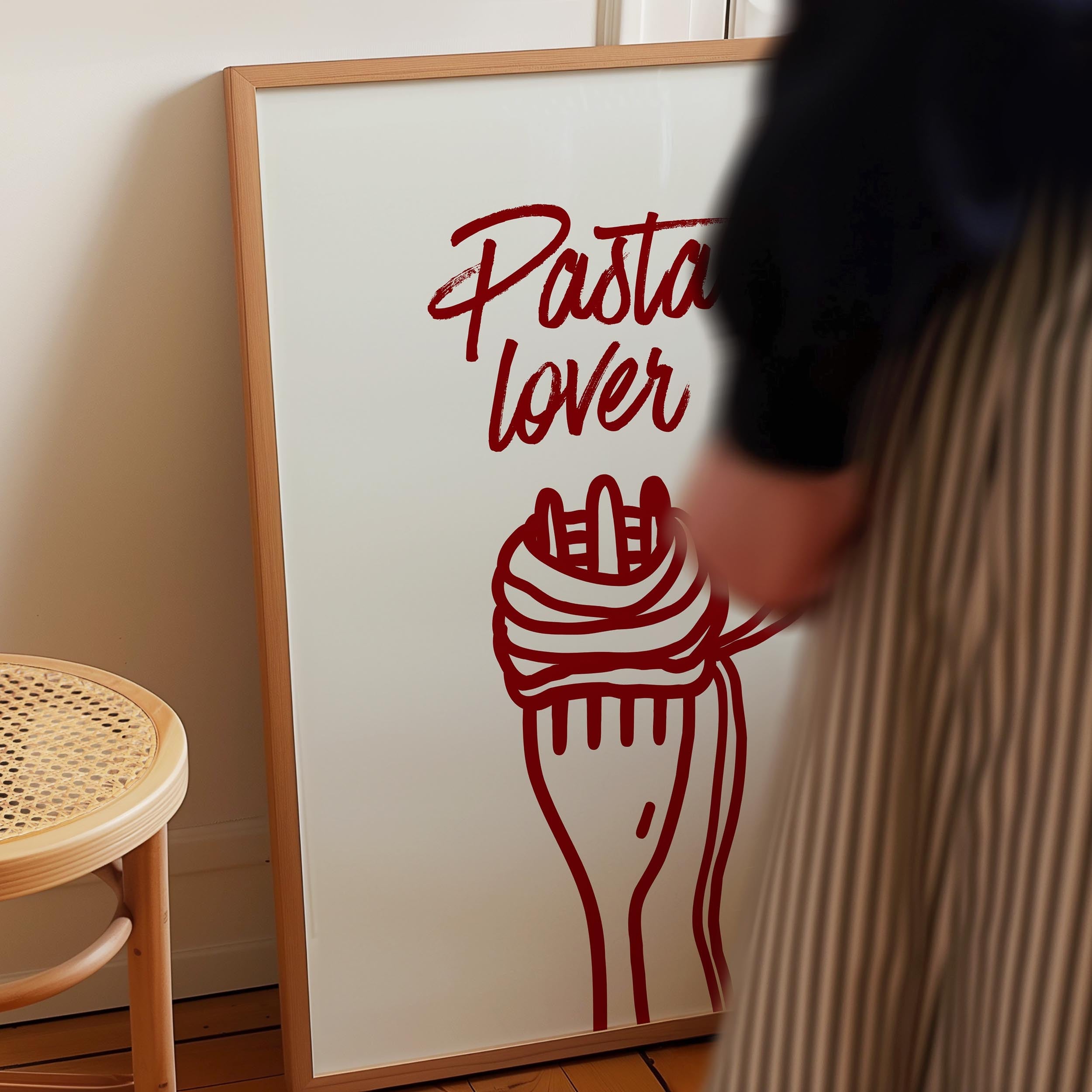 a person standing next to a framed poster with a red design of a fork and pasta.