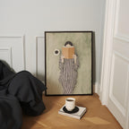 a cozy corner with a framed painting of a person reading a book, a cup of coffee, and a stack of books on the floor.