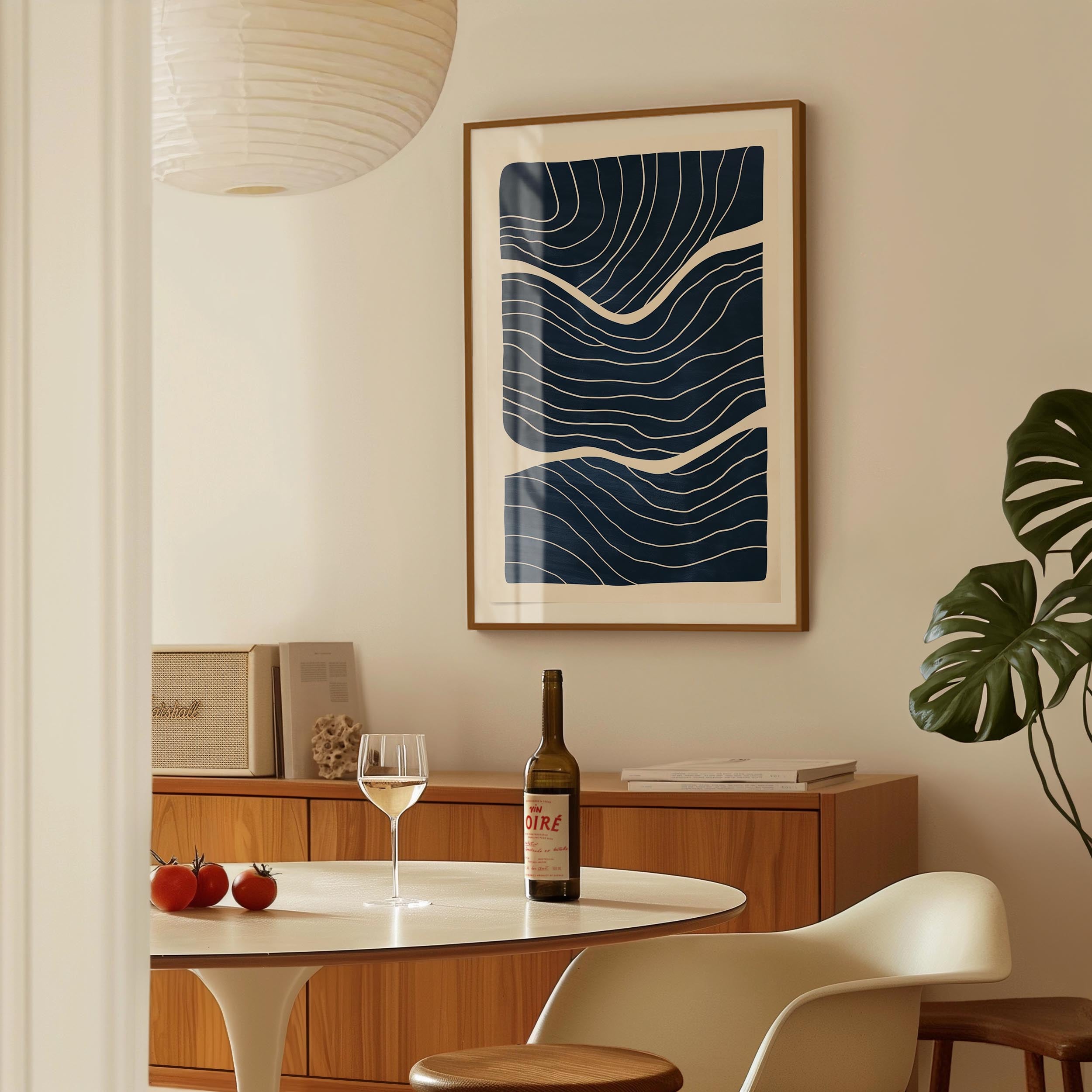 a dining area with a table, a bottle of wine, and a framed abstract art piece on the wall.