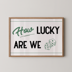 A framed poster with the text "How LUCKY ARE WE" and two dice graphics.