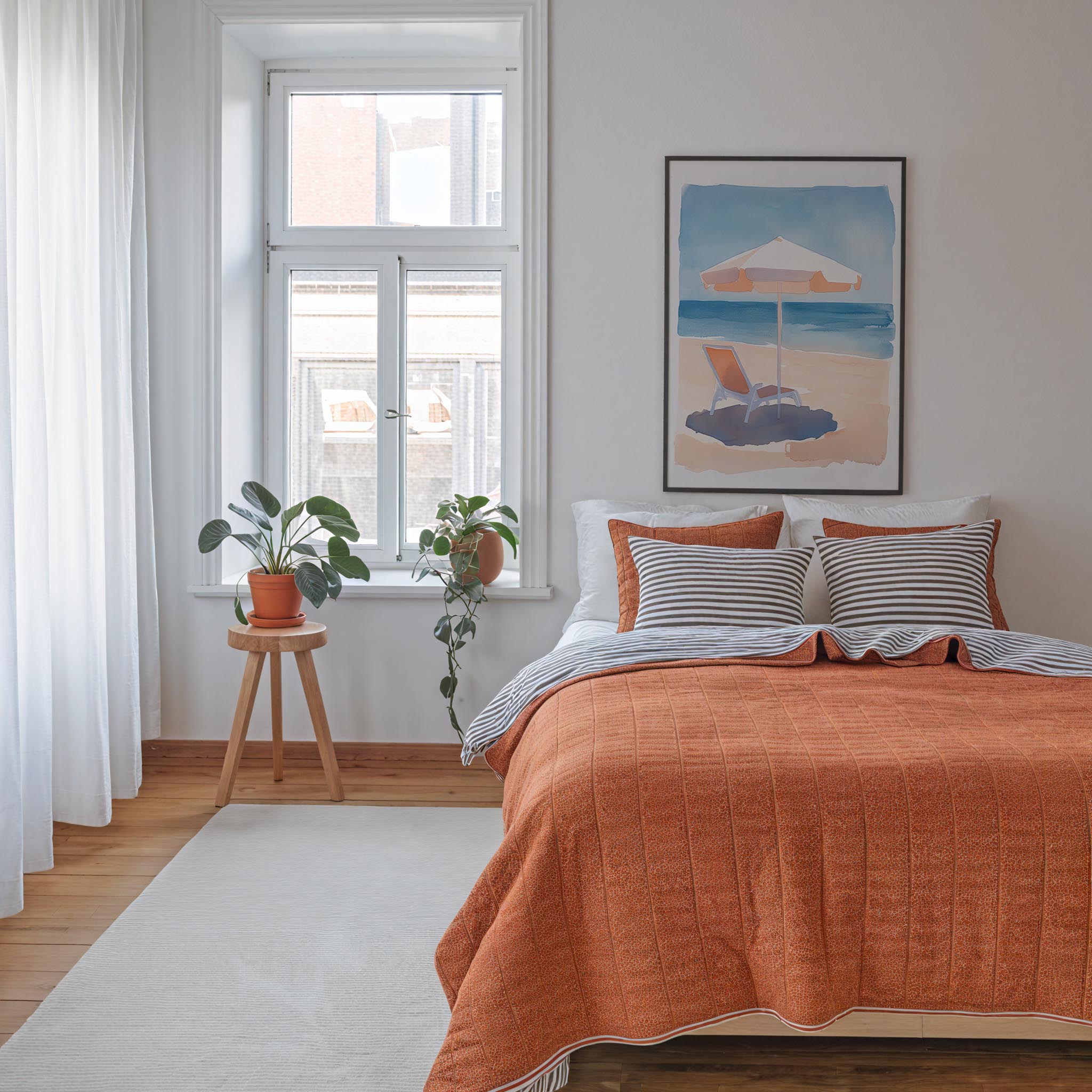 a cozy bedroom with a large bed, a window with a view of the beach, and a painting of a beach scene on the wall.