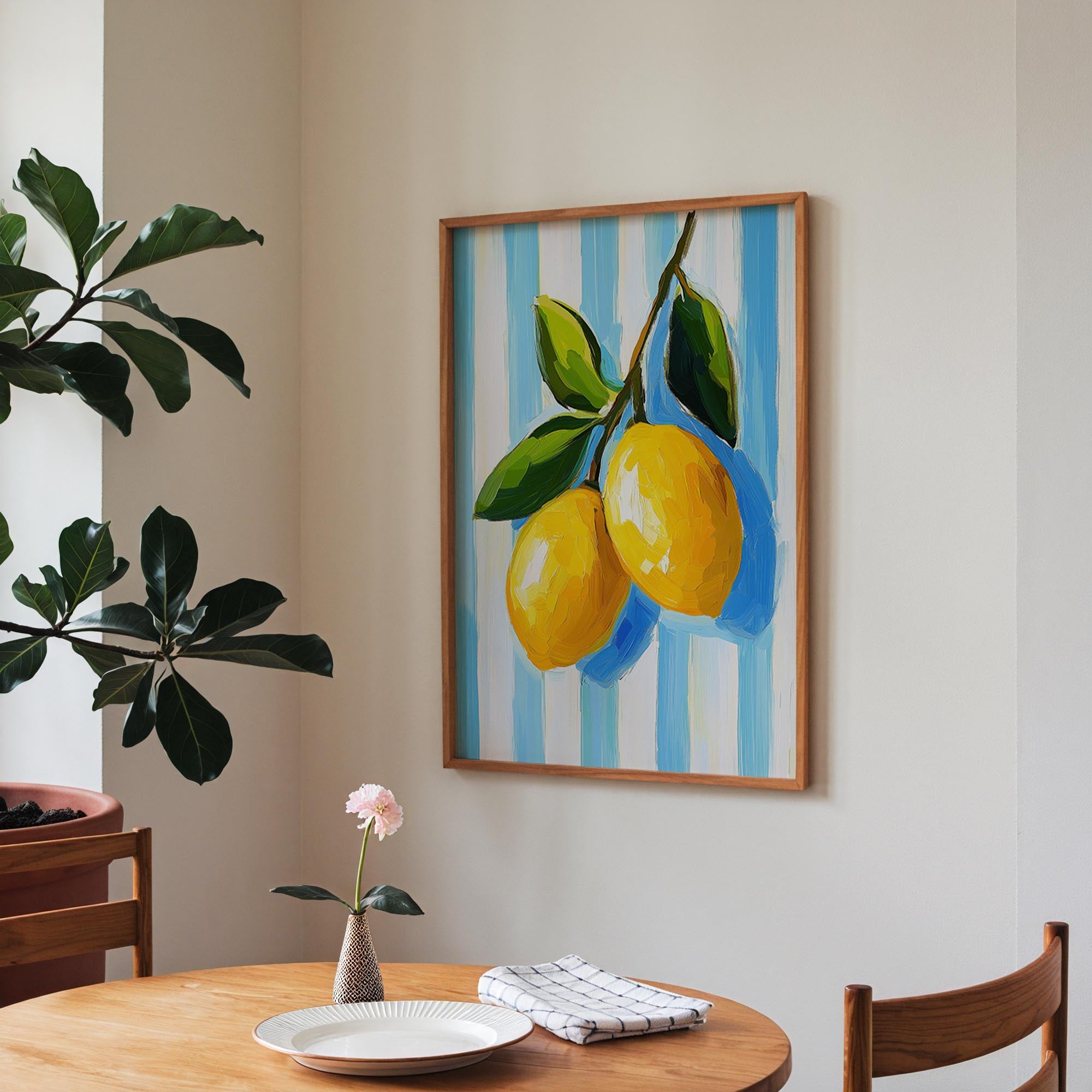a wooden table with a white plate, a vase with a pink flower, and a framed painting of two lemons hanging on the wall above the table.