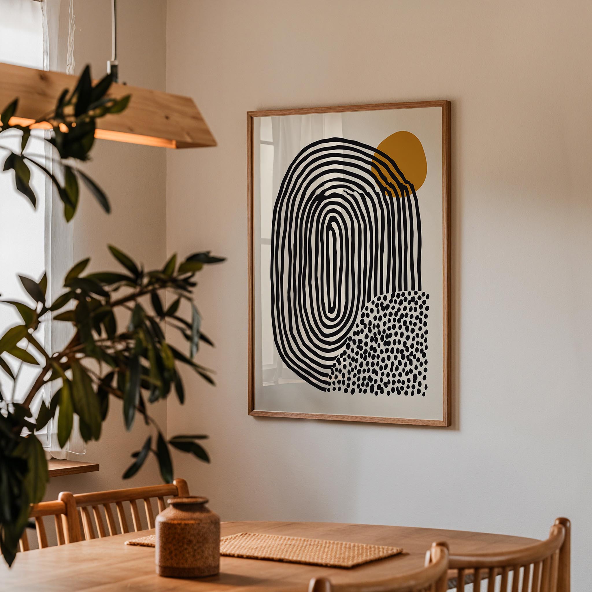 a wooden dining table with a woven placemat, a potted plant, and a framed abstract art piece hanging on the wall above the table.