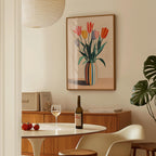a dining room with a table set for two, a bottle of wine, and a framed painting of colorful tulips hanging on the wall.