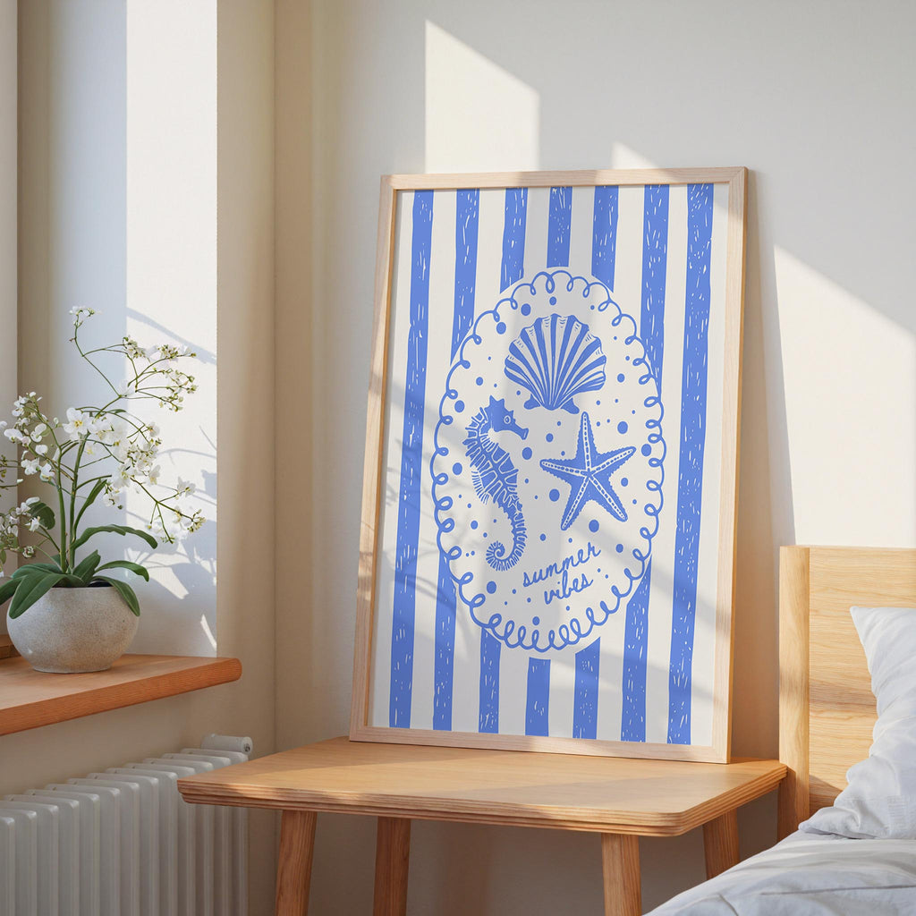 a framed artwork with a blue and white design, including a seahorse, starfish, and seashell, hanging on a wall in a bedroom.
