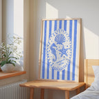 a framed artwork with a blue and white design, including a seahorse, starfish, and seashell, hanging on a wall in a bedroom.